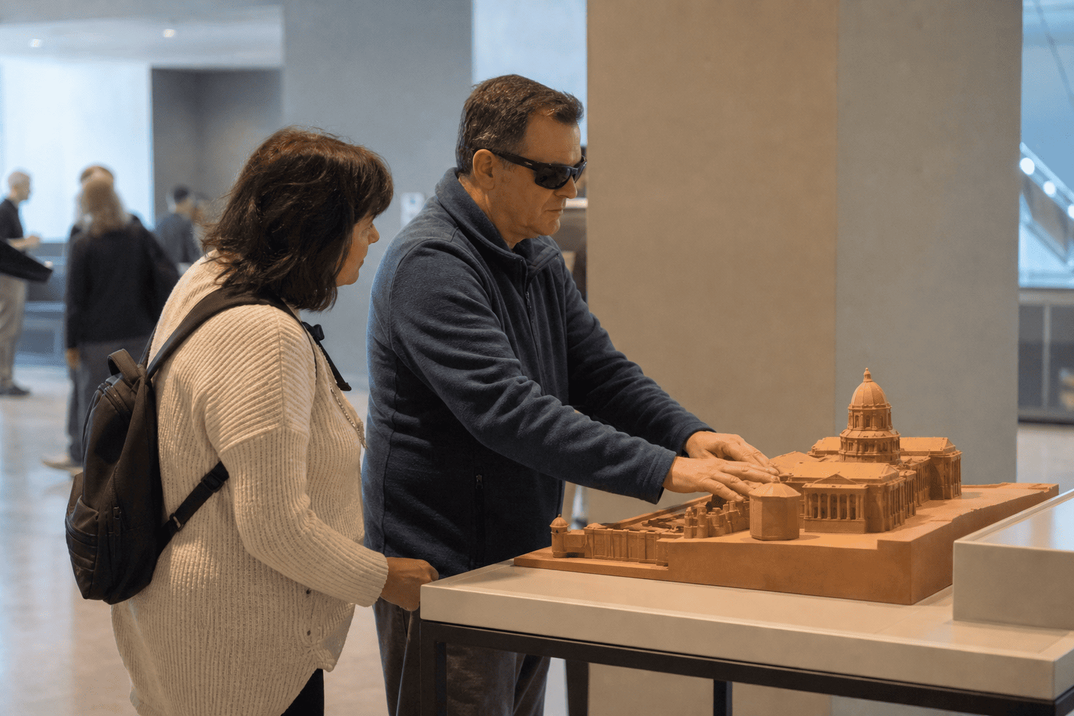 A blind museum visitor explores an architectural model by touch
