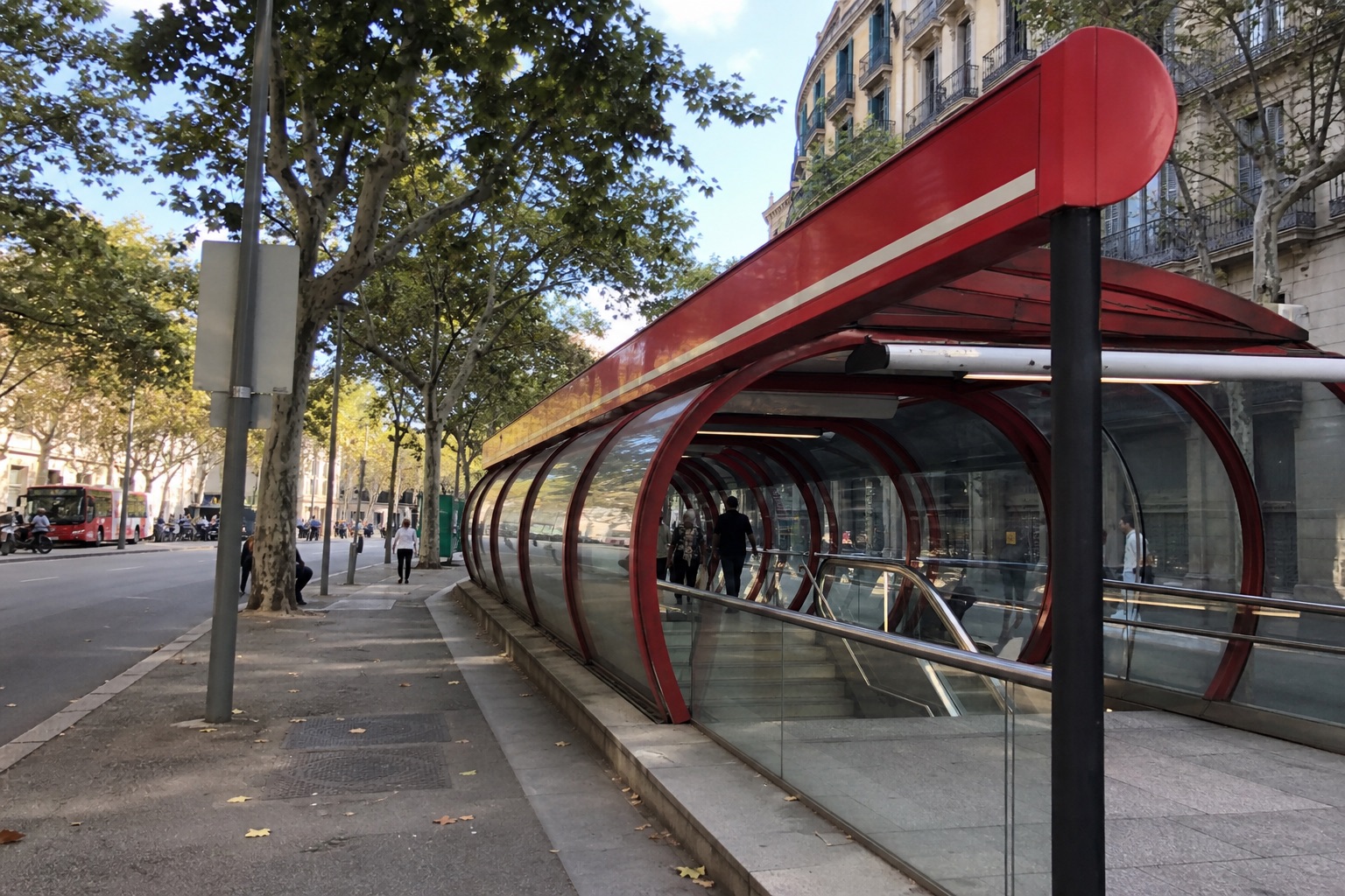 Phone snapshot: a red metro entrance canopy on a wide Barcelona avenue