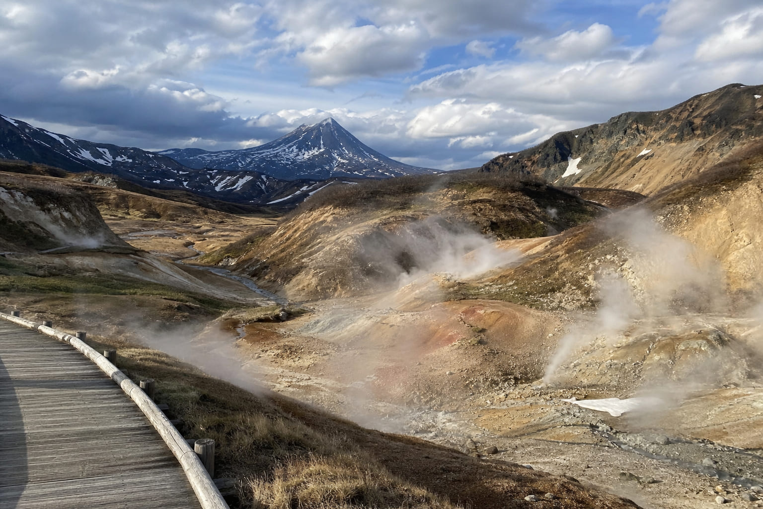 Kamchatka geyser valley: steam rising over thermal pools with a snow-capped volcano in the background, casual smartphone travel photo