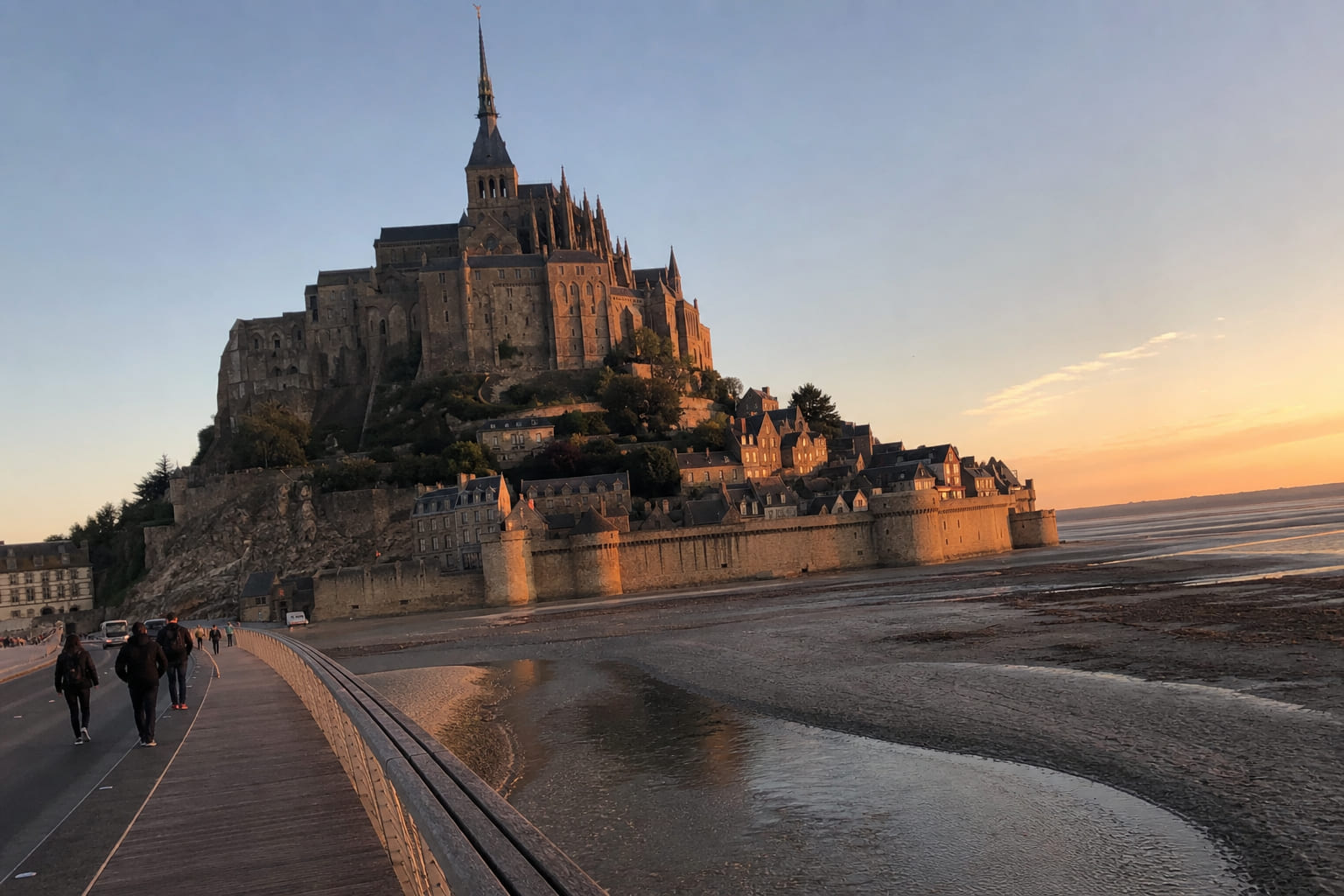 Mont Saint-Michel: iconic stop on a Normandy driving route Mont Saint-Michel abbey in Normandy — casual tourist smartphone photo from the tidal causeway at sunset