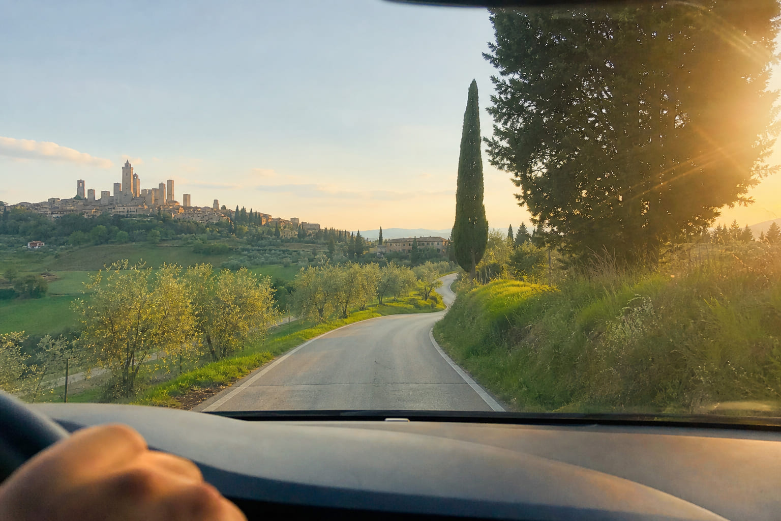 Tuscany country road with cypress trees — casual tourist smartphone photo through a rental car windshield