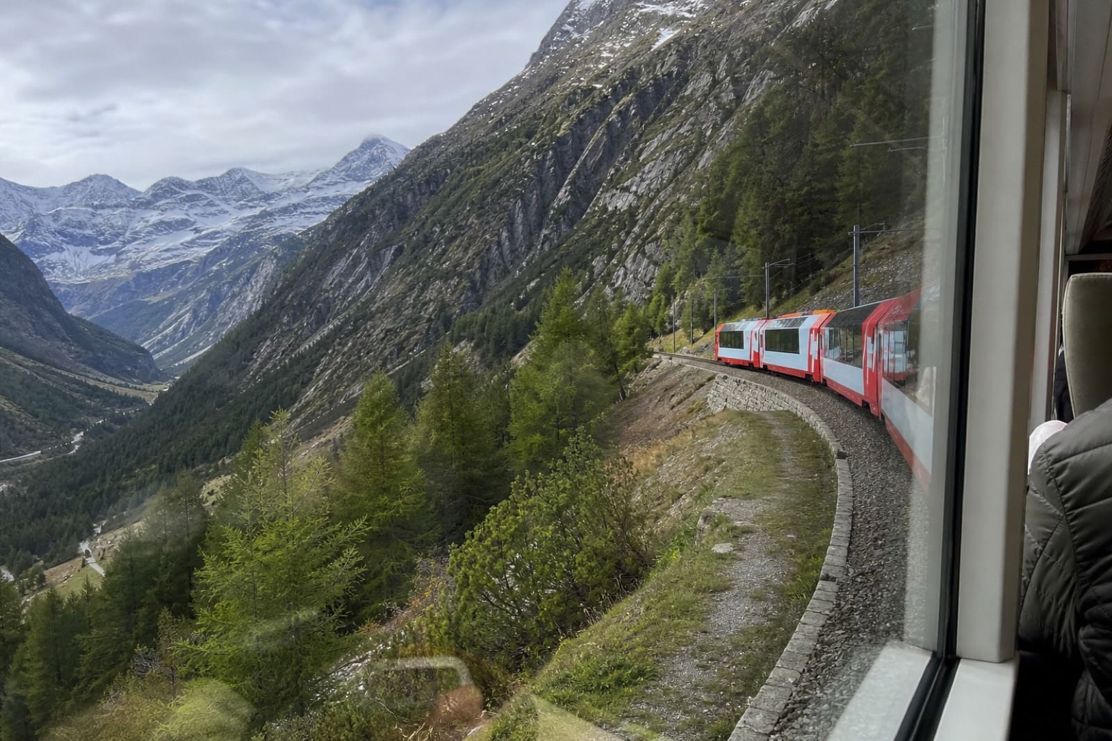 Glacier Express: панорамные окна и альпийские долины — классический кадр «медленного» scenic-экспресса. Вид на Альпы из окна панорамного поезда Glacier Express — снимок туриста на телефон