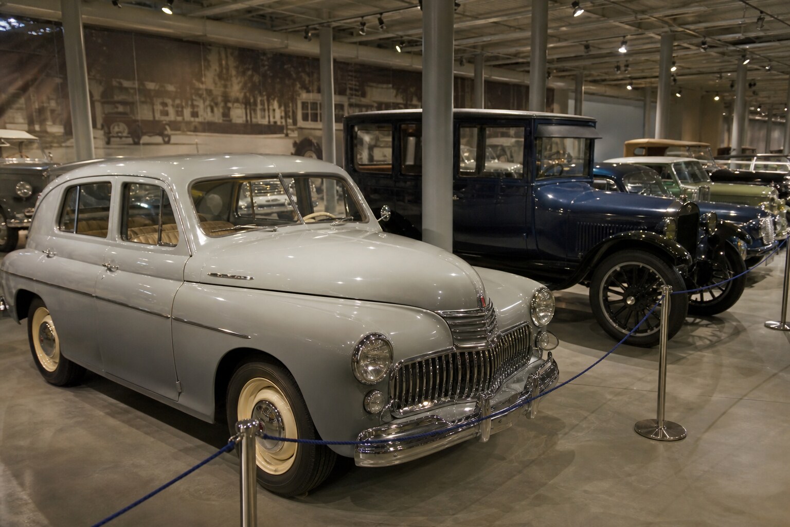Classic cars in a museum gallery photographed casually on a smartphone