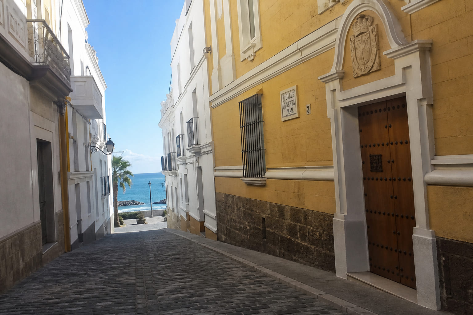 Phone snapshot of a narrow cobbled street in old Cádiz looking toward the Atlantic Ocean