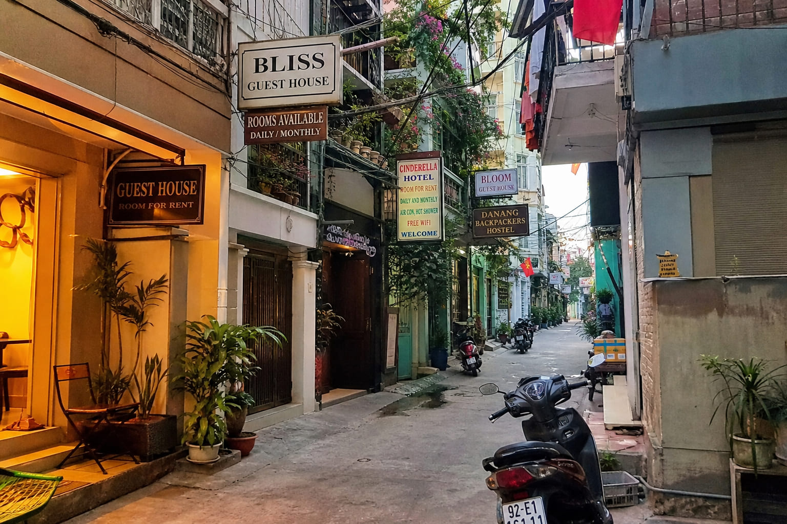 Budget lodging in Asia: guesthouses and hostels Narrow Asian street with guesthouse and hostel signs: casual tourist smartphone photo