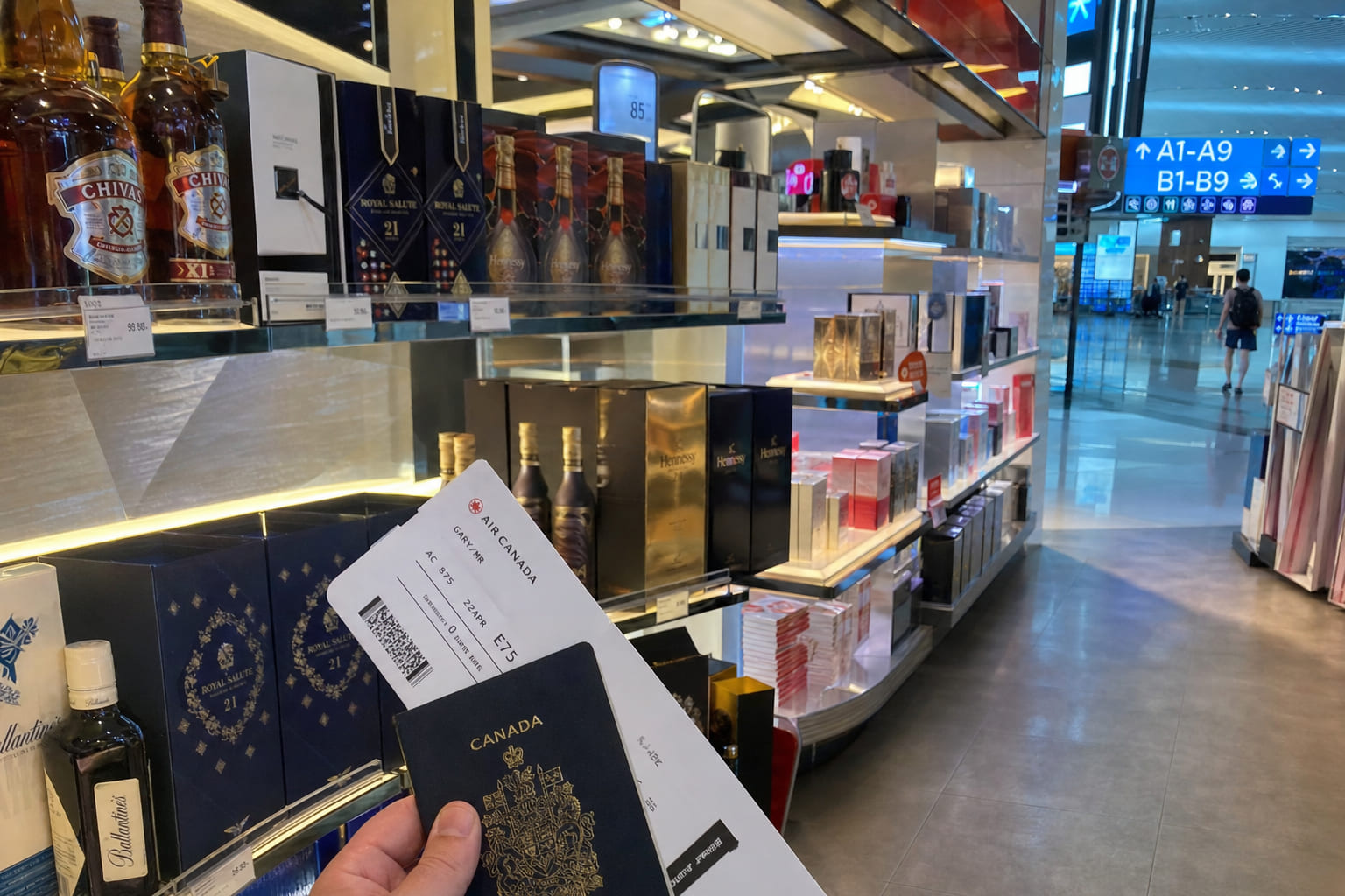 Снимок на телефон в зоне Duty Free аэропорта: витрины с алкоголем и парфюмерией, ценники, посадочный талон в руке