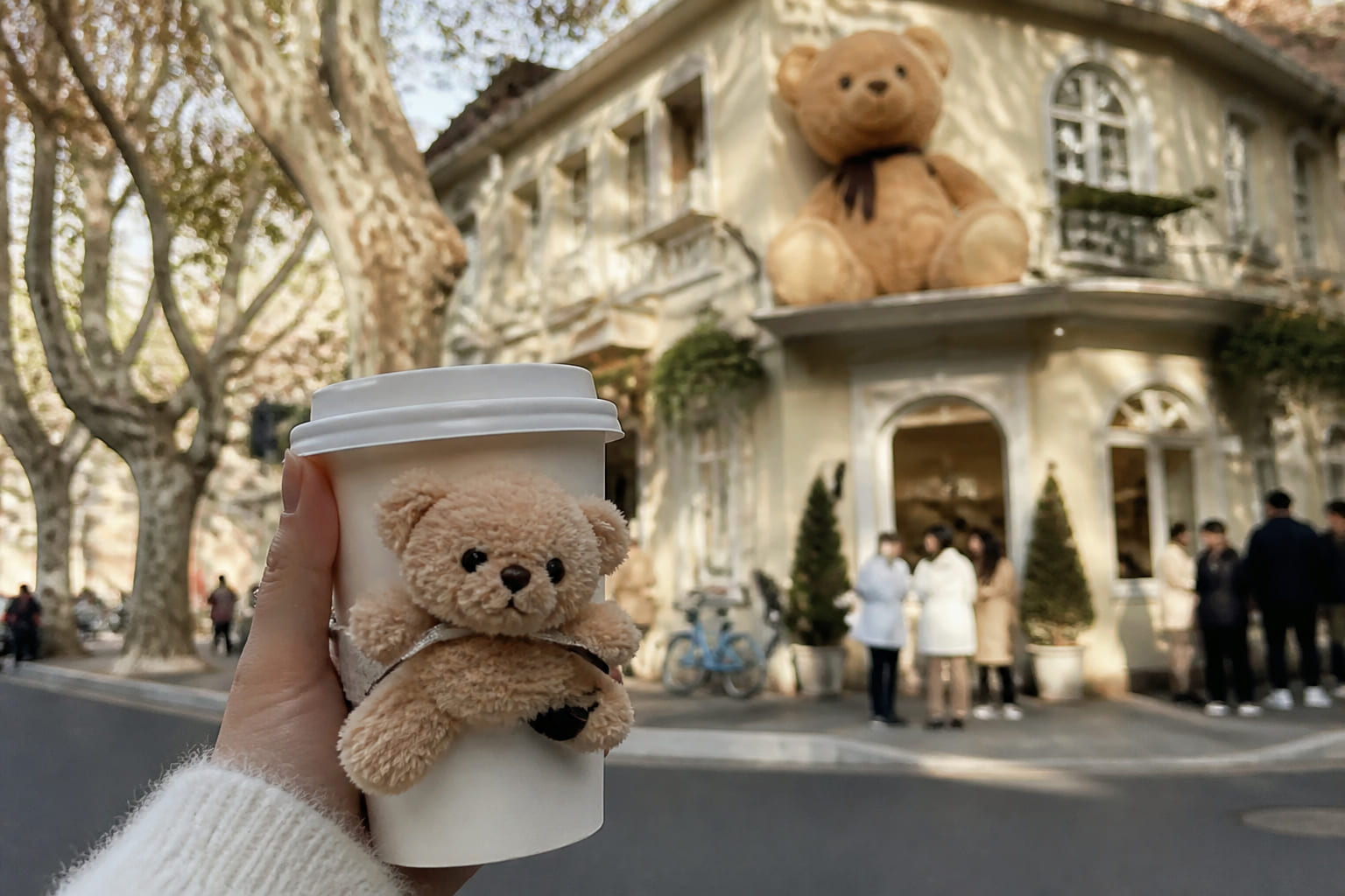 Tourist phone photo: coffee cup with a plush teddy bear against a bright Anfu Road café facade in Shanghai